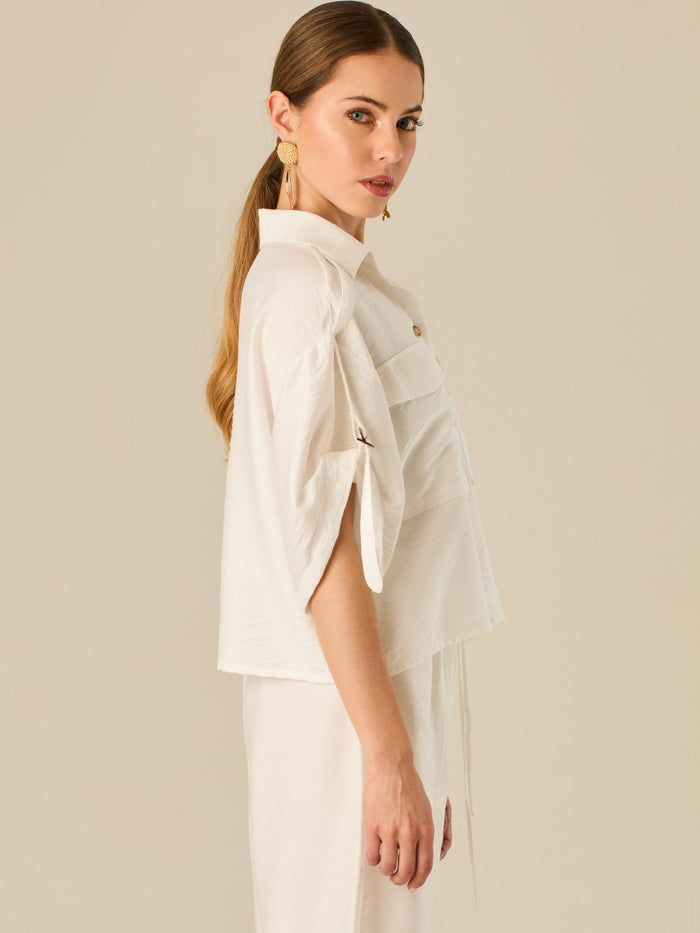 Blusa de silueta relajada con botones al frente, bolsillos tipo parche y mangas con detalle de amarre que aporta un aire desenfadado y chic. Su estilo versátil la convierte en una opción perfecta para looks casuales con un toque sofisticado.

Detalles:

Color: Blanco