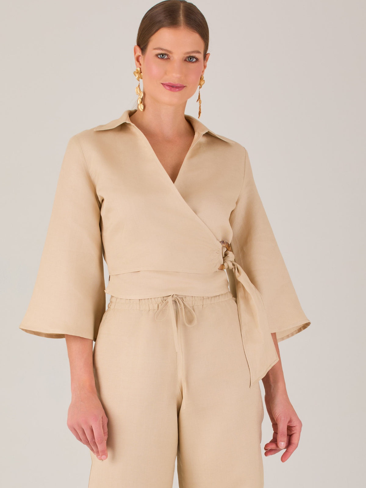 Blusa cruzada de manga tres cuartos y corte recto. Tiene cuello clásico y se ajusta con un lazo lateral que añade un toque elegante y moderno.