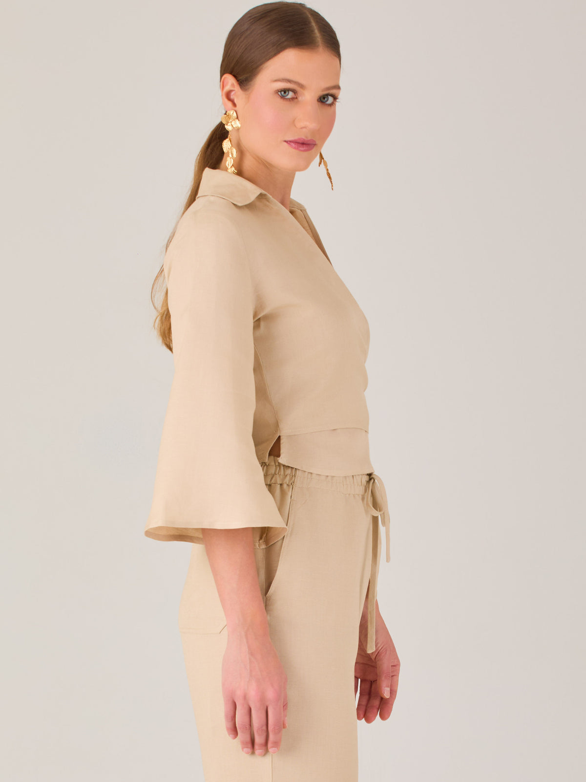 Blusa cruzada de manga tres cuartos y corte recto. Tiene cuello clásico y se ajusta con un lazo lateral que añade un toque elegante y moderno.