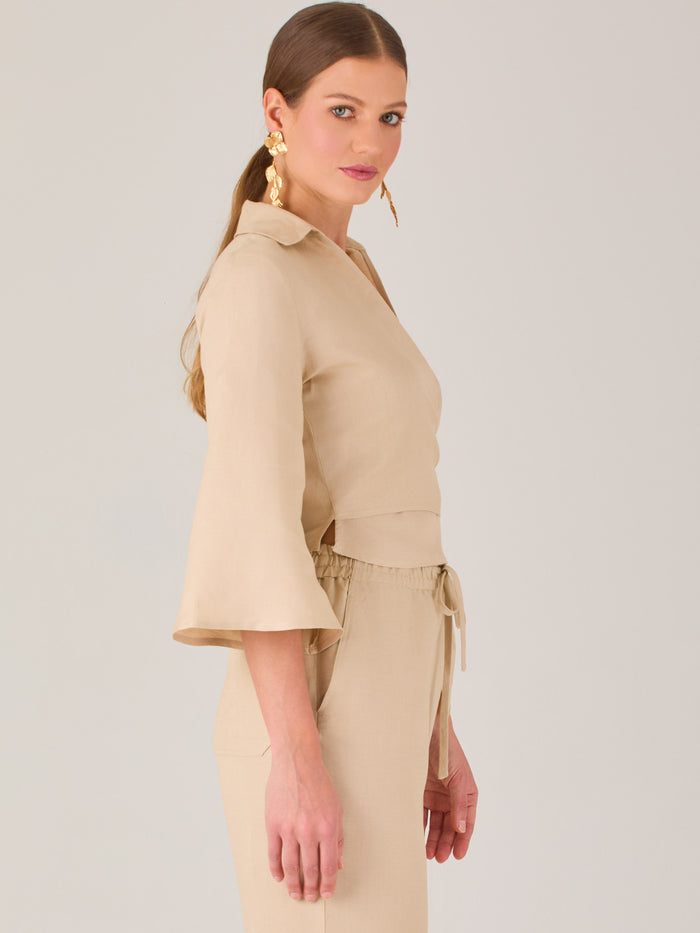 Blusa cruzada de manga tres cuartos y corte recto. Tiene cuello clásico y se ajusta con un lazo lateral que añade un toque elegante y moderno.