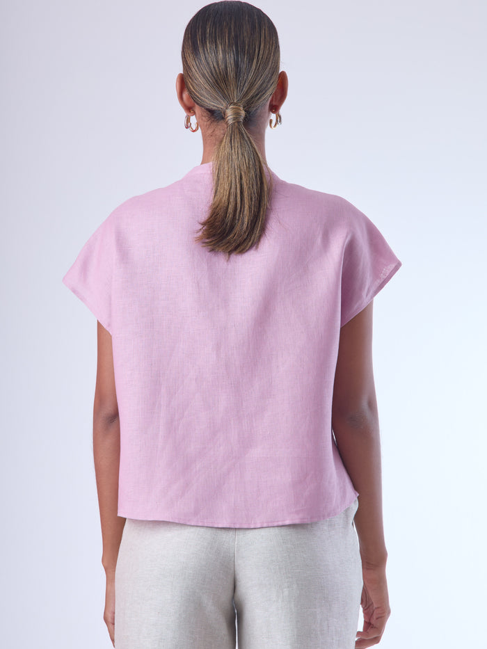 Blusa de silueta recta con manga corta tipo caída y estructura relajada. Cuenta con cuello que se cierra con un pequeño broche metálico decorativos estilo sobrio la hace versátil y elegante, ideal para atuendos casuales o más refinados.