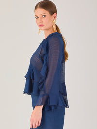 Ligera y romántica, esta blusa de textura vaporosa destaca por sus volantes en capas que aportan movimiento y fluidez. El escote en V y las mangas amplias con acabado ondulado añaden un toque delicado y sofisticado. Ideal para ocasiones especiales, cenas o estilismos casuales con un aire femenino y refinado.