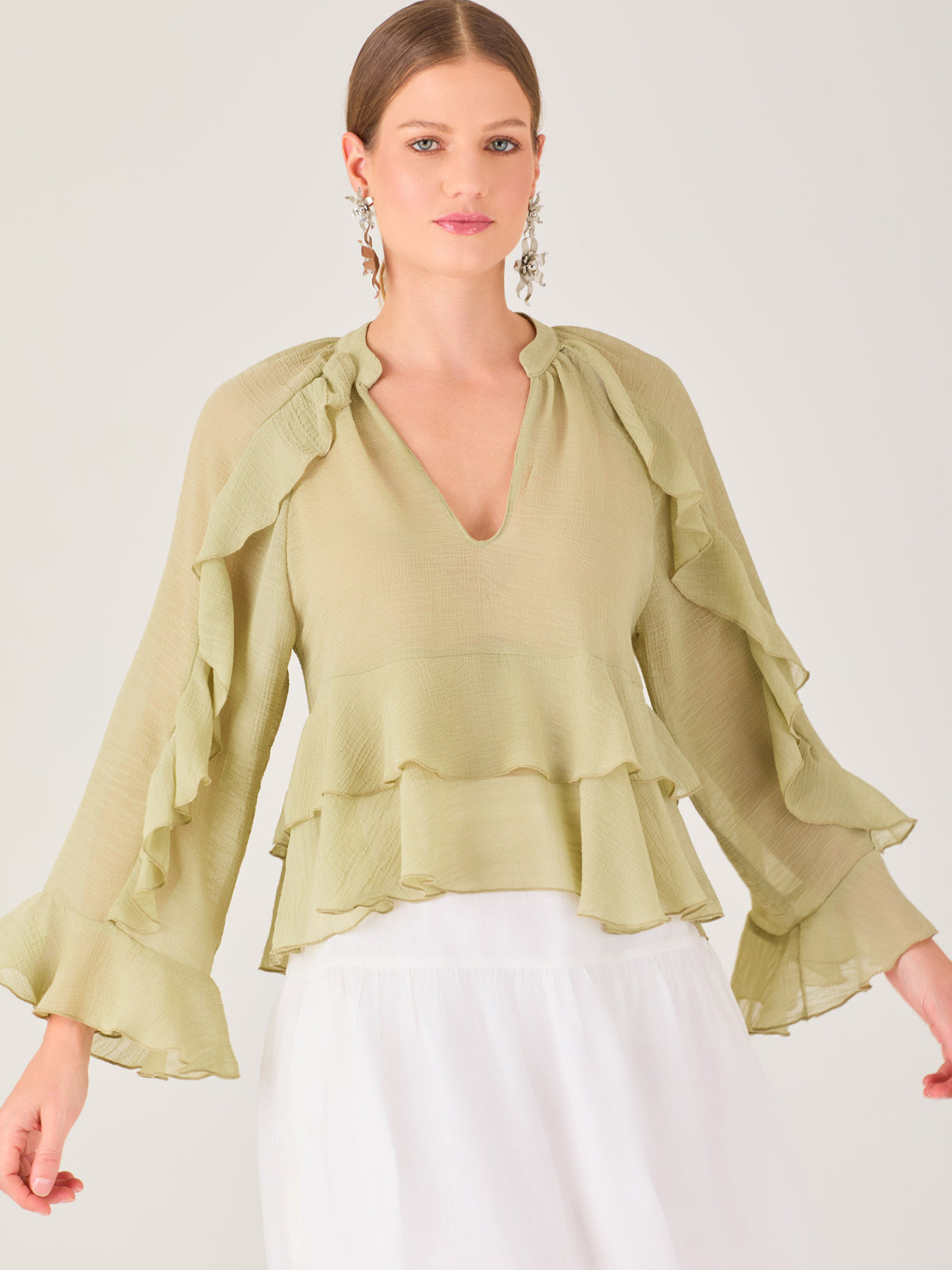 Ligera y romántica, esta blusa de textura vaporosa destaca por sus volantes en capas que aportan movimiento y fluidez. El escote en V y las mangas amplias con acabado ondulado añaden un toque delicado y sofisticado. Ideal para ocasiones especiales, cenas o estilismos casuales con un aire femenino y refinado.