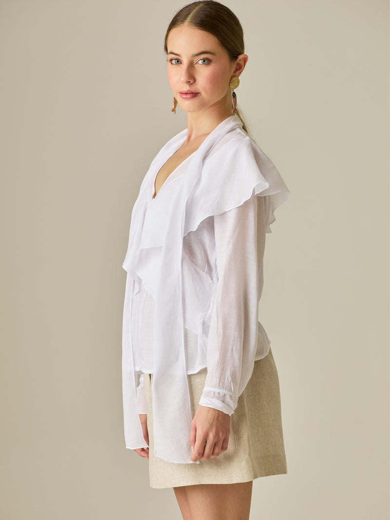 Blusa de manga larga con detalle de volantes en el escote y lazo largo para anudar. Su diseño ligero y delicado aporta movimiento y sofisticación, ideal para un look femenino con un aire romántico y moderno.

Detalles: