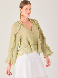 Ligera y romántica, esta blusa de textura vaporosa destaca por sus volantes en capas que aportan movimiento y fluidez. El escote en V y las mangas amplias con acabado ondulado añaden un toque delicado y sofisticado. Ideal para ocasiones especiales, cenas o estilismos casuales con un aire femenino y refinado.