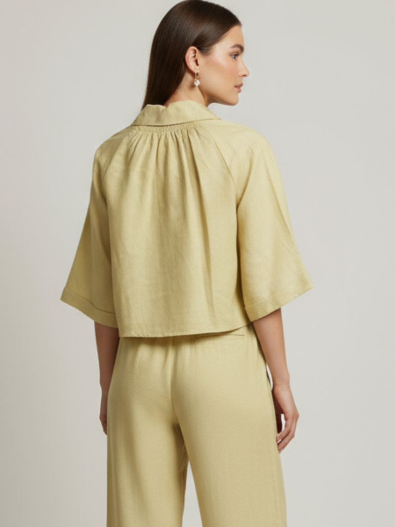 Blusa cropped, manga amplia tipo kimono y cuello camisero; botonadura frontal, ajuste relajado y caída ligera—fresca y versátil para un look casual-elegante