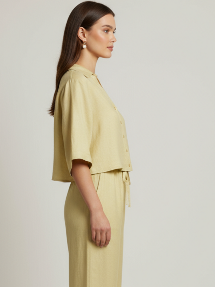 Blusa cropped, manga amplia tipo kimono y cuello camisero; botonadura frontal, ajuste relajado y caída ligera—fresca y versátil para un look casual-elegante