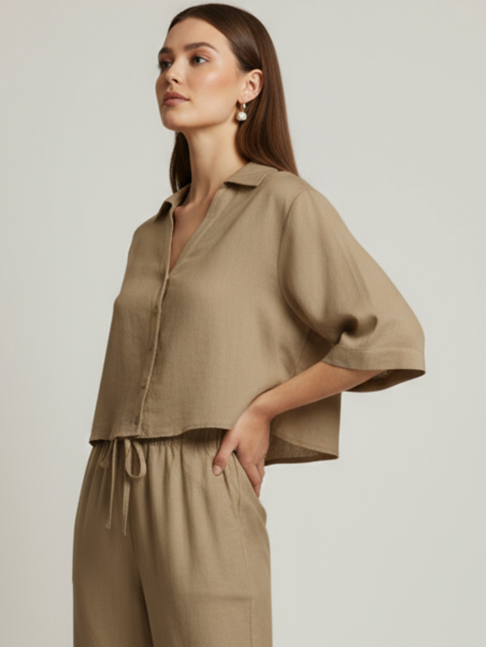 Blusa cropped, manga amplia tipo kimono y cuello camisero; botonadura frontal, ajuste relajado y caída ligera—fresca y versátil para un look casual-elegante