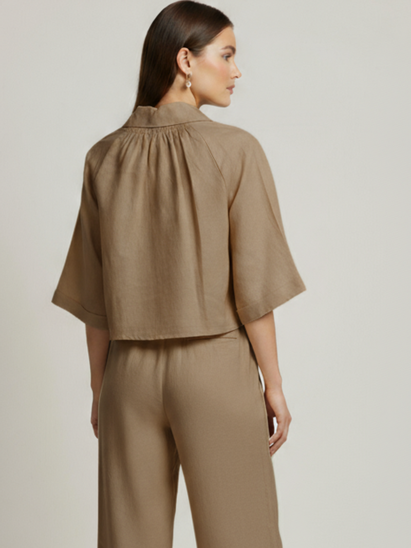 Blusa cropped, manga amplia tipo kimono y cuello camisero; botonadura frontal, ajuste relajado y caída ligera—fresca y versátil para un look casual-elegante