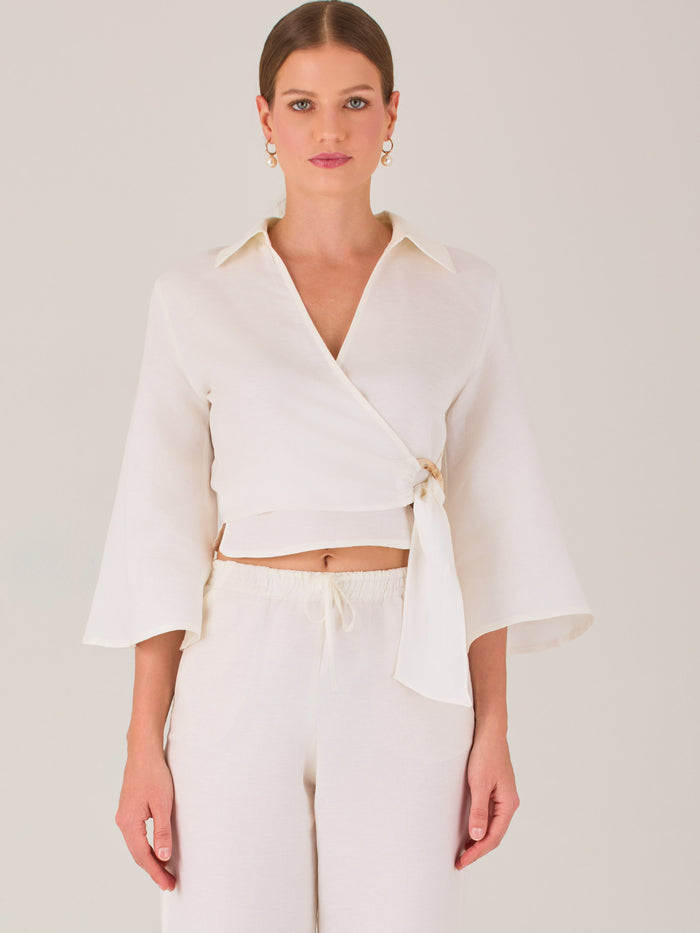Blusa cruzada de manga tres cuartos y corte recto. Tiene cuello clásico y se ajusta con un lazo lateral que añade un toque elegante y moderno.

Detalles:

Color: Blanco

Material: 52% Lino 48% Rayón