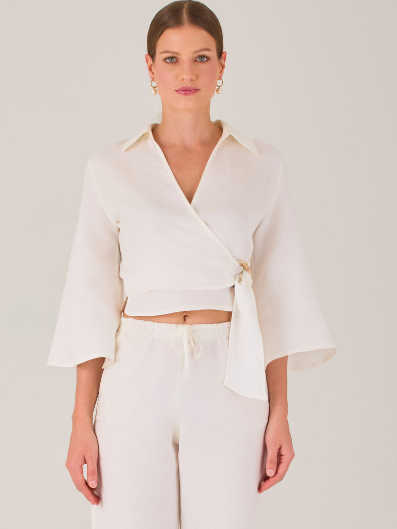 Blusa cruzada de manga tres cuartos y corte recto. Tiene cuello clásico y se ajusta con un lazo lateral que añade un toque elegante y moderno.

Detalles:

Color: Blanco

Material: 52% Lino 48% Rayón