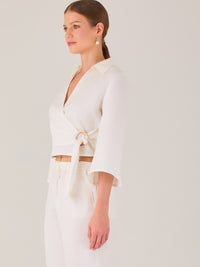 Blusa cruzada de manga tres cuartos y corte recto. Tiene cuello clásico y se ajusta con un lazo lateral que añade un toque elegante y moderno.

Detalles:

Color: Blanco

Material: 52% Lino 48% Rayón