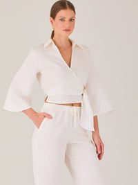 Blusa cruzada de manga tres cuartos y corte recto. Tiene cuello clásico y se ajusta con un lazo lateral que añade un toque elegante y moderno.

Detalles:

Color: Blanco

Material: 52% Lino 48% Rayón