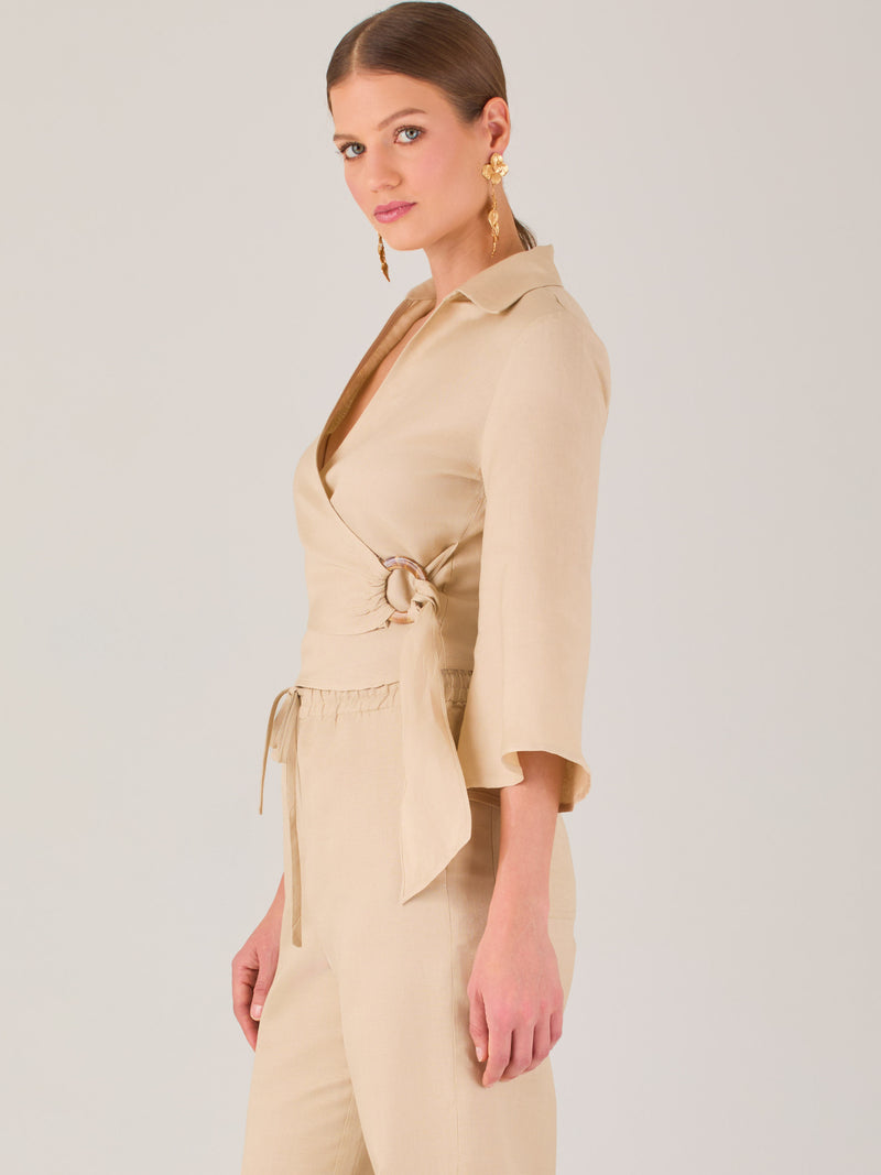 Blusa cruzada de manga tres cuartos y corte recto. Tiene cuello clásico y se ajusta con un lazo lateral que añade un toque elegante y moderno.
