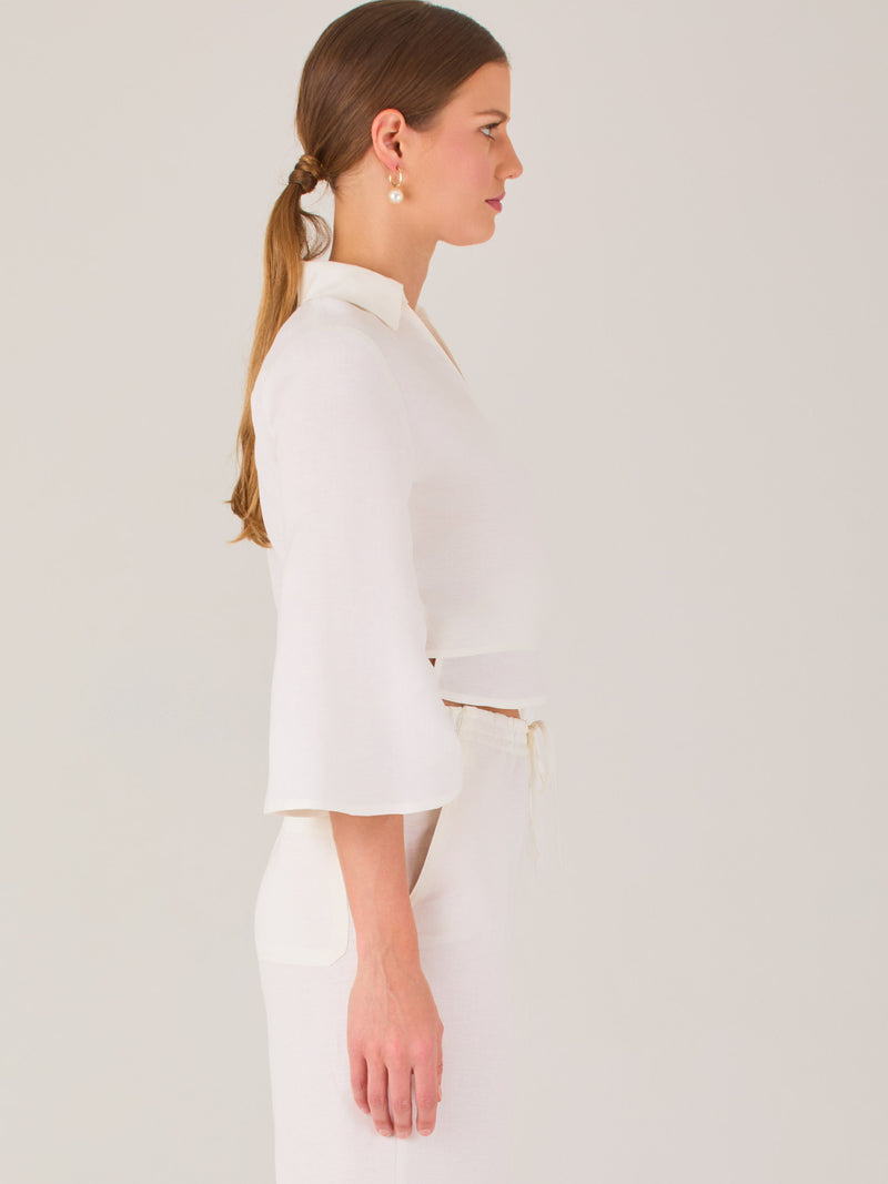 Blusa cruzada de manga tres cuartos y corte recto. Tiene cuello clásico y se ajusta con un lazo lateral que añade un toque elegante y moderno.

Detalles:

Color: Blanco

Material: 52% Lino 48% Rayón