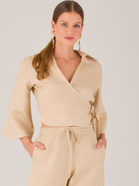 Blusa cruzada de manga tres cuartos y corte recto. Tiene cuello clásico y se ajusta con un lazo lateral que añade un toque elegante y moderno.