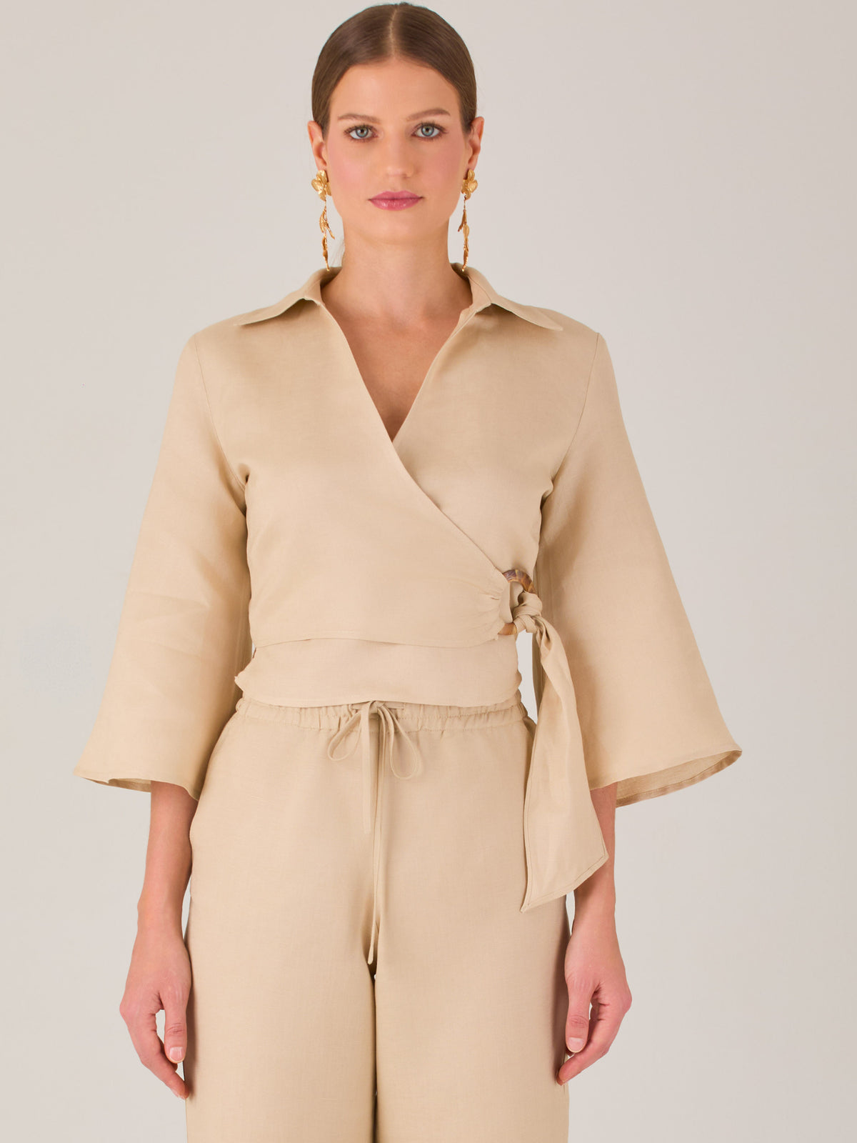 Blusa cruzada de manga tres cuartos y corte recto. Tiene cuello clásico y se ajusta con un lazo lateral que añade un toque elegante y moderno.