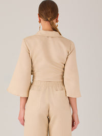 Blusa cruzada de manga tres cuartos y corte recto. Tiene cuello clásico y se ajusta con un lazo lateral que añade un toque elegante y moderno.