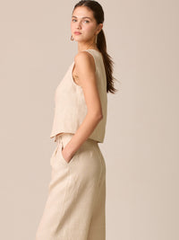 Blusa tipo chaleco sin mangas, con escote redondo y cierre frontal de botones forrados, entallada en la parte superior y con dobladillo ligeramente curvado que aporta un acabado elegante y estructurado
