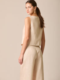 Blusa tipo chaleco sin mangas, con escote redondo y cierre frontal de botones forrados, entallada en la parte superior y con dobladillo ligeramente curvado que aporta un acabado elegante y estructurado