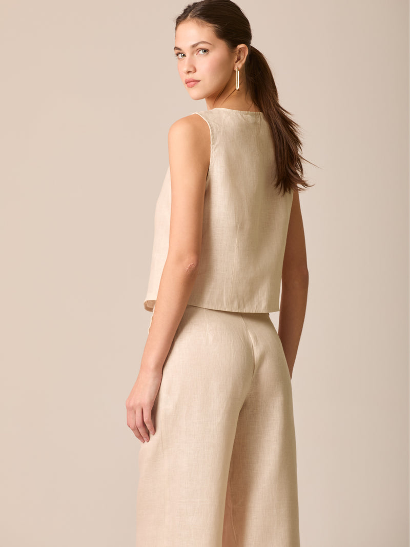 Blusa tipo chaleco sin mangas, con escote redondo y cierre frontal de botones forrados, entallada en la parte superior y con dobladillo ligeramente curvado que aporta un acabado elegante y estructurado