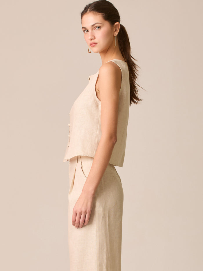 Blusa tipo chaleco sin mangas, con escote redondo y cierre frontal de botones forrados, entallada en la parte superior y con dobladillo ligeramente curvado que aporta un acabado elegante y estructurado