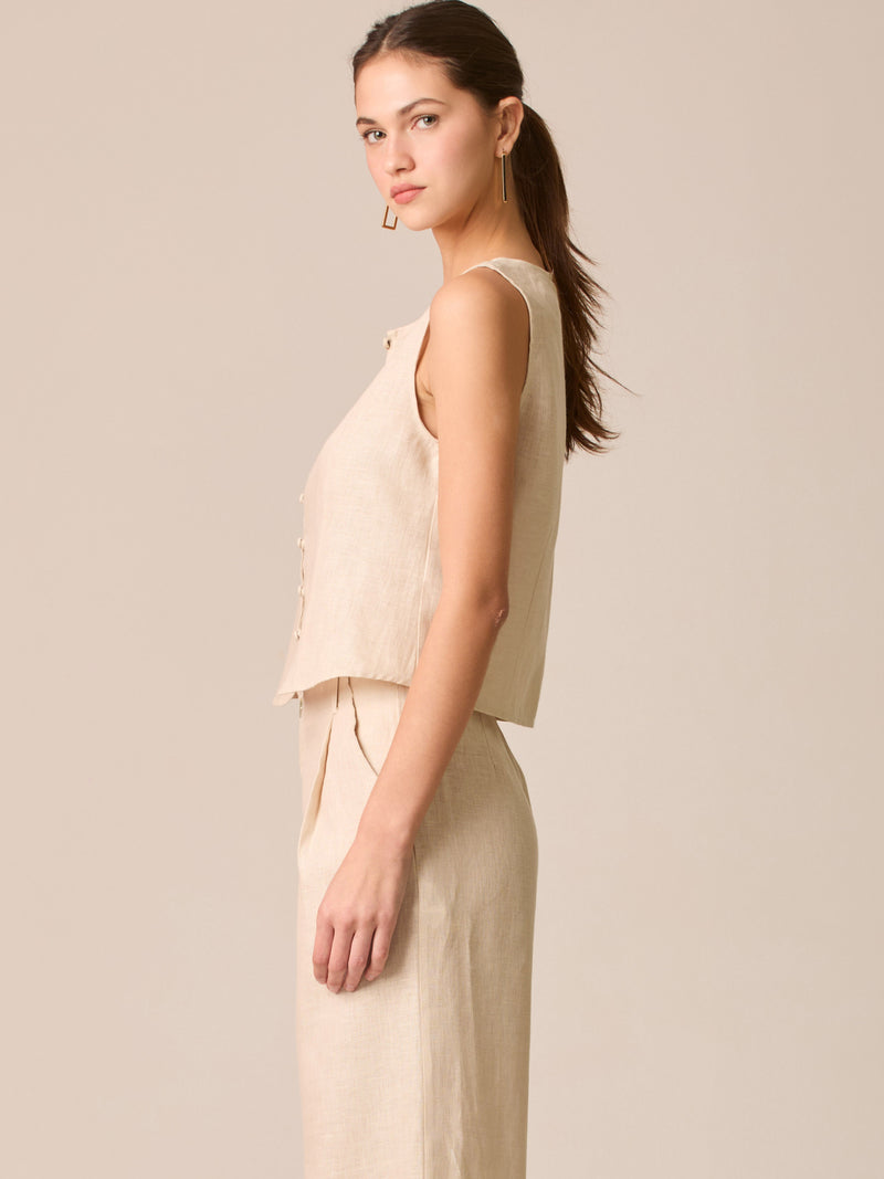 Blusa tipo chaleco sin mangas, con escote redondo y cierre frontal de botones forrados, entallada en la parte superior y con dobladillo ligeramente curvado que aporta un acabado elegante y estructurado