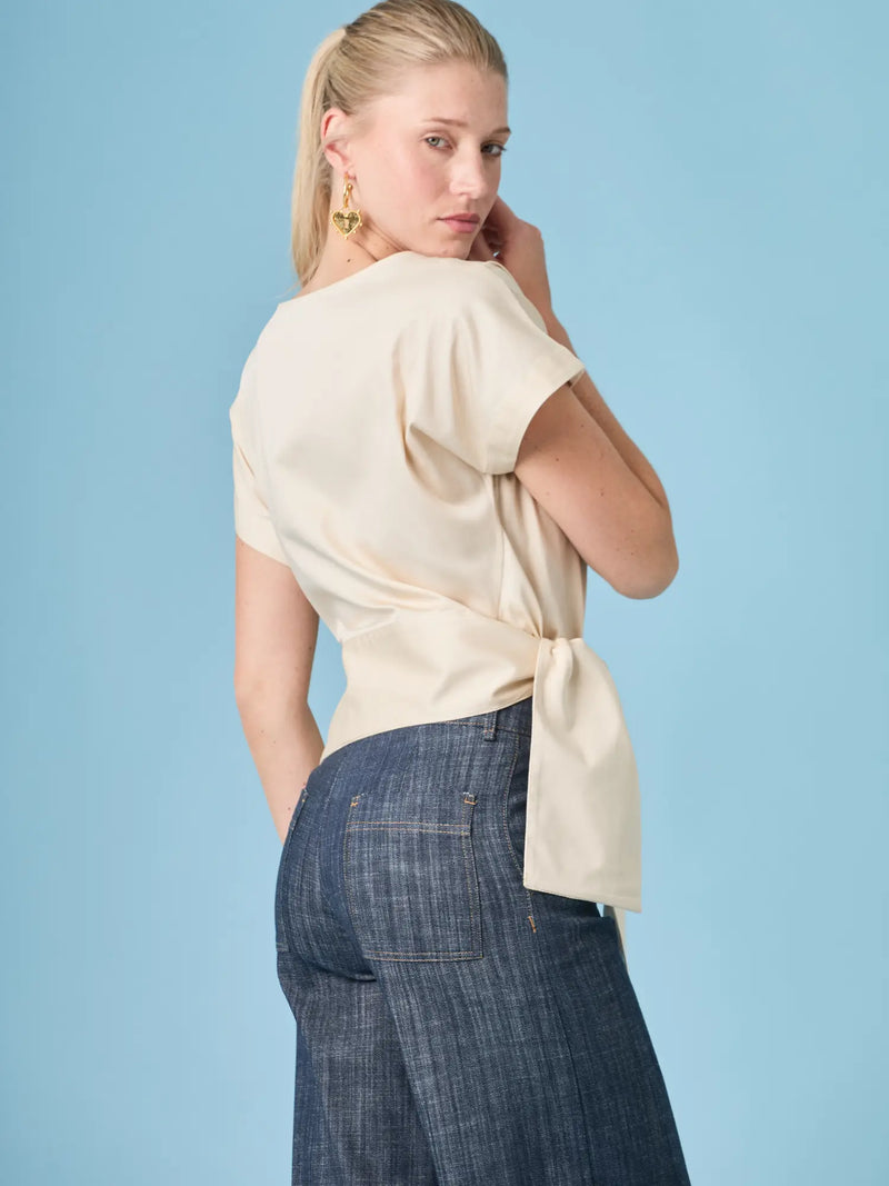 Blusa Shantall Crema para mujer con diseño minimalista y detalle de lazo lateral sofisticado.