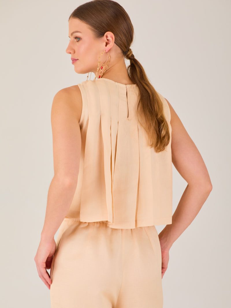 Blusa sin mangas de silueta recta con delicados pliegues frontales que aportan movimiento y un acabado refinado.

Detalles: