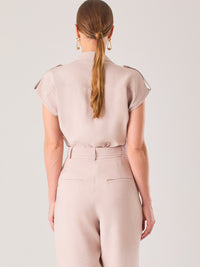 Blusa blanca de estilo camisero con un diseño moderno y minimalista. Cuenta con cuello clásico, tapeta oculta para los botones y mangas cortas tipo caída con detalle de charreteras en los hombros. Posee dos bolsillos de parche en el pecho que le aportan un toque utilitario y estructurado. Su corte recto y fluido la hace ideal tanto para looks casuales como elegantes