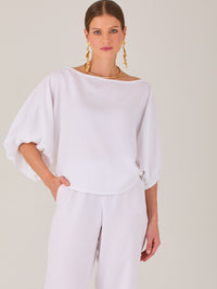 Sofisticada y atemporal, esta blusa de silueta recta se caracteriza por su escote cerrado, líneas limpias y mangas tres cuartos con efecto globo. El diseño pulido la convierte en una prenda versátil para combinar con prendas sastre o looks relajados, ideal para ambientes laborales o estilismos casuales con elegancia natural.