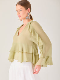 Ligera y romántica, esta blusa de textura vaporosa destaca por sus volantes en capas que aportan movimiento y fluidez. El escote en V y las mangas amplias con acabado ondulado añaden un toque delicado y sofisticado. Ideal para ocasiones especiales, cenas o estilismos casuales con un aire femenino y refinado.