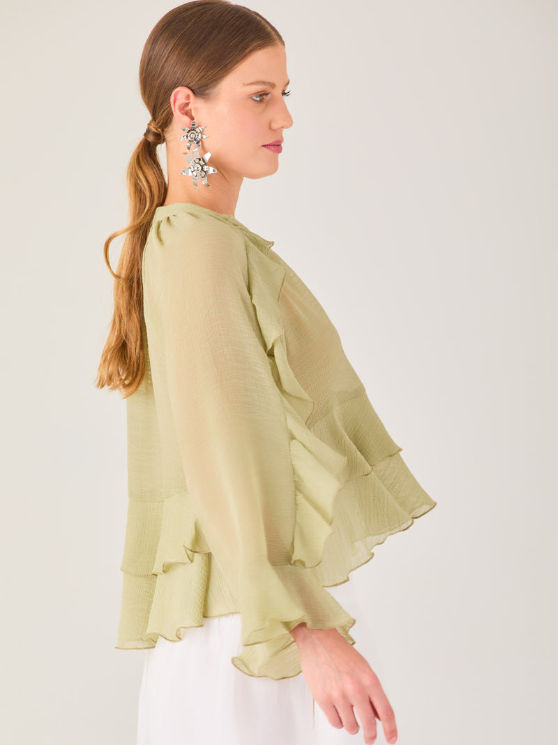 Ligera y romántica, esta blusa de textura vaporosa destaca por sus volantes en capas que aportan movimiento y fluidez. El escote en V y las mangas amplias con acabado ondulado añaden un toque delicado y sofisticado. Ideal para ocasiones especiales, cenas o estilismos casuales con un aire femenino y refinado.