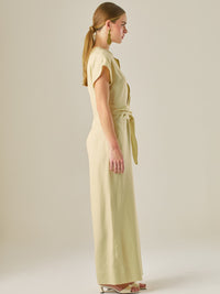 Este enterizo presenta un diseño elegante y minimalista, ideal para ocasiones casuales con estilo o eventos diurnos sofisticados. Confeccionado en un tono beige claro, tiene un corte relajado con mangas tipo kimono, cuello redondo y un diseño limpio sin botones ni cierres visibles en el frente. La prenda se ajusta en la cintura con un cinturón del mismo tejido, que se anuda al frente, creando una silueta favorecedora. El pantalón es de pierna ancha y caída fluida, lo que aporta comodidad y movimiento. Compl