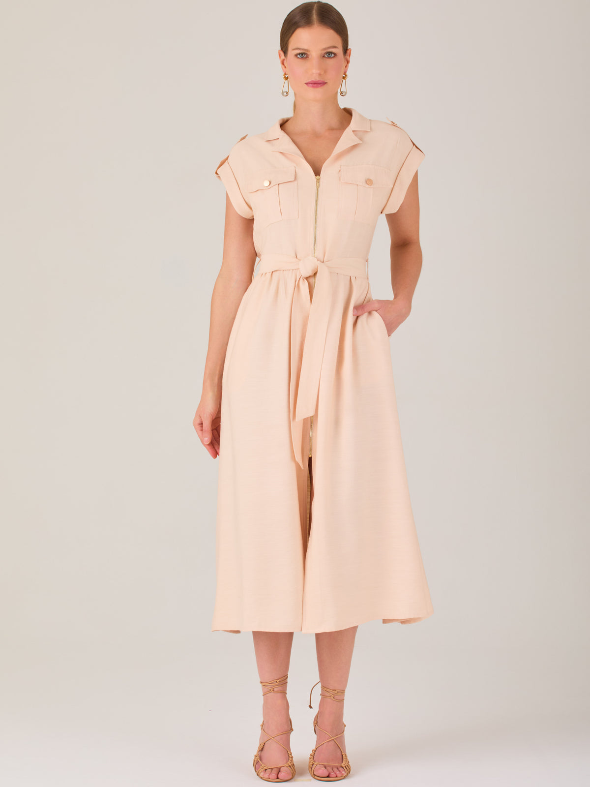 Diseño atemporal con carácter. Este vestido midi sin mangas combina estructura y feminidad con detalles utilitarios como bolsillos frontales, cierre metálico y solapas marcadas. El cinturón en la cintura permite ajustar la silueta, creando un look pulido ideal para la oficina, eventos casuales o estilismos urbanos con elegancia natural.

Detalles: