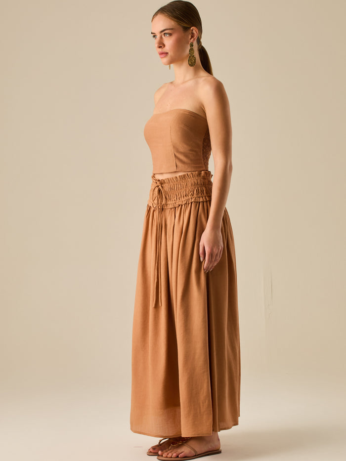 Falda larga de tiro alto con pretina fruncida y lazo ajustable, ideal para un look relajado con elegancia sutil. Su caída fluida y textura ligera aportan movimiento y frescura, perfecta para estilismos sofisticados con esencia natural.

Detalles:

Color: Camel

Material: 82% Rayon 18% Nylon