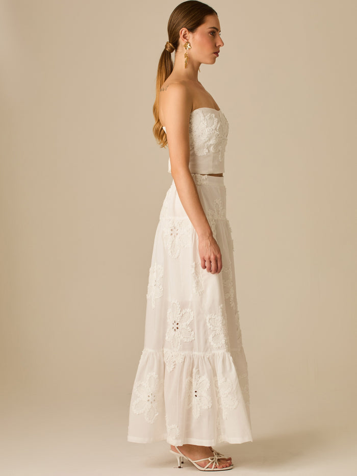 Falda larga con bordado floral en relieve y volantes sutiles que aportan movimiento. Su diseño romántico y fresco la convierte en una pieza ideal para looks veraniegos con un toque sofisticado y femenino.

Color: Blanco

Material:100% Algodon