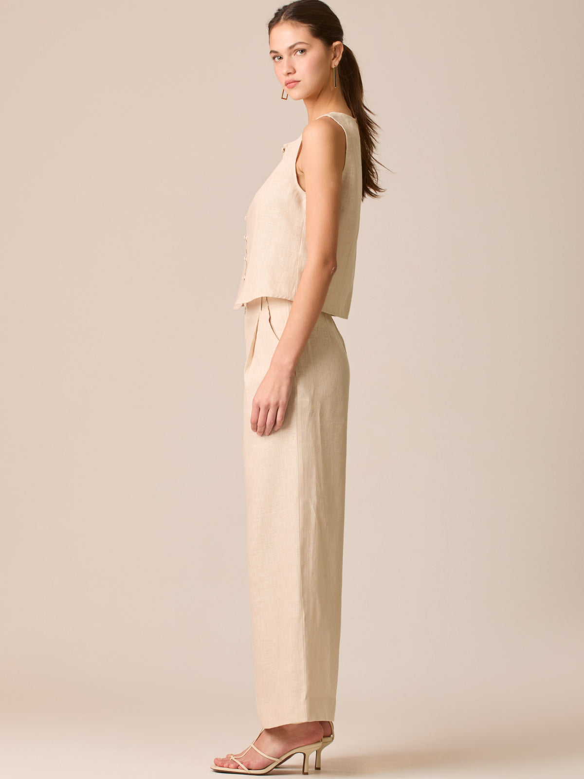 Pantalón de tiro medio con pretina plana, pinzas frontales y corte recto amplio hasta el tobillo, confeccionado en un tejido liviano de textura natural que aporta un look sofisticado y relajado