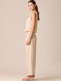 Pantalón de tiro medio con pretina plana, pinzas frontales y corte recto amplio hasta el tobillo, confeccionado en un tejido liviano de textura natural que aporta un look sofisticado y relajado