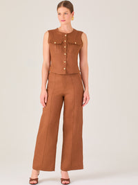Este pantalón presenta un corte de pierna ancha y recta, confeccionado en una tela estructurada de tono marrón cálido. Tiene un diseño elegante y minimalista, con cintura de talle medio y cierre delantero oculto. Las líneas limpias y la ausencia de detalles recargados lo hacen ideal para un look pulido y sofisticado. Incluye bolsillos discretos laterales y se ajusta ligeramente en la cadera, cayendo con amplitud hasta los tobillos. Su estilo versátil lo convierte en una prenda perfecta tanto para contextos 