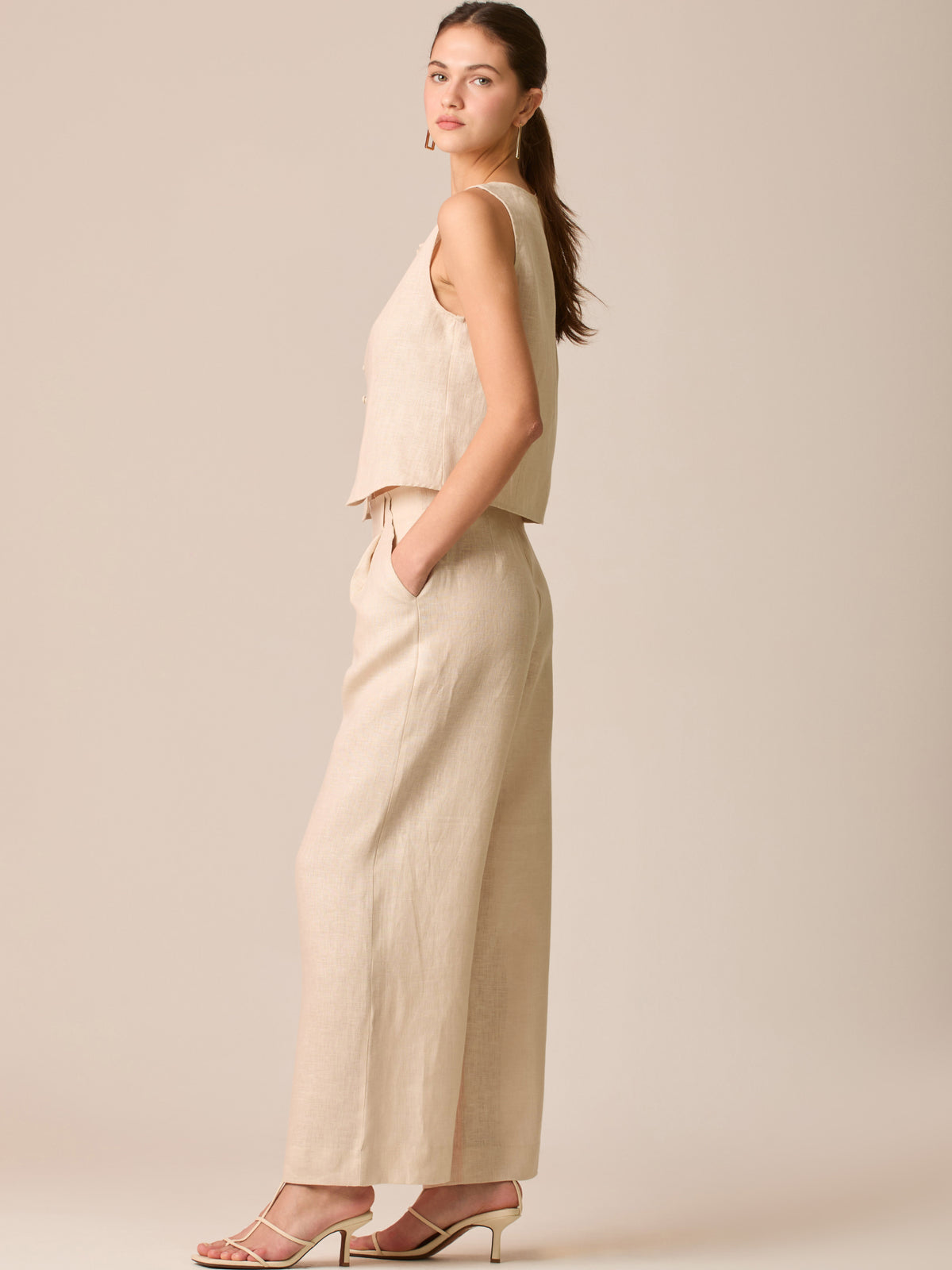 Pantalón de tiro medio con pretina plana, pinzas frontales y corte recto amplio hasta el tobillo, confeccionado en un tejido liviano de textura natural que aporta un look sofisticado y relajado