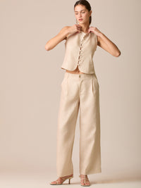 Pantalón de tiro medio con pretina plana, pinzas frontales y corte recto amplio hasta el tobillo, confeccionado en un tejido liviano de textura natural que aporta un look sofisticado y relajado