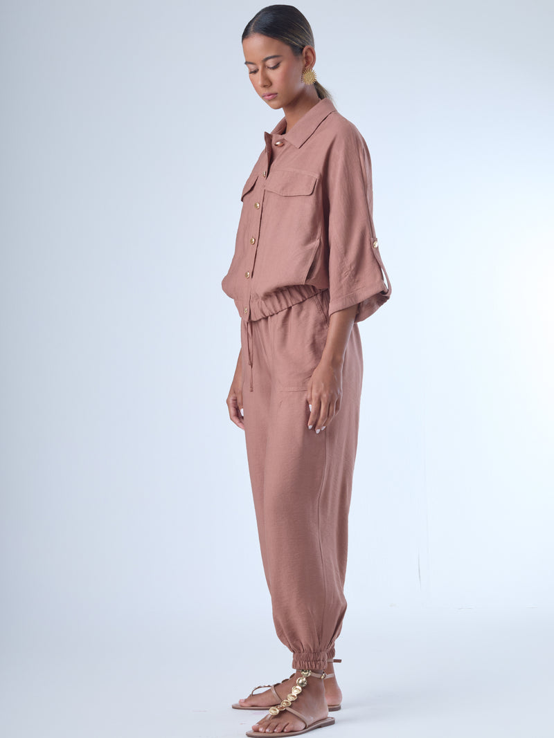 Cómodo y versátil, este pantalón tipo jogger presenta una silueta relajada con ajuste en tobillos y cintura elástica para máximo confort. Los bolsillos frontales tipo parche y la textura suave de la tela lo hacen ideal para looks casuales con un toque elevado. Perfecto para combinar con blusas fluidas o camisas estructuradas, en días de descanso o estilismos urbanos sofisticados.