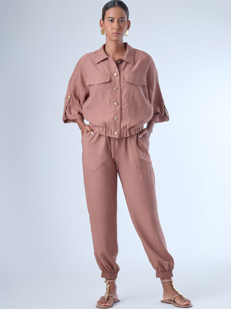 Cómodo y versátil, este pantalón tipo jogger presenta una silueta relajada con ajuste en tobillos y cintura elástica para máximo confort. Los bolsillos frontales tipo parche y la textura suave de la tela lo hacen ideal para looks casuales con un toque elevado. Perfecto para combinar con blusas fluidas o camisas estructuradas, en días de descanso o estilismos urbanos sofisticados.