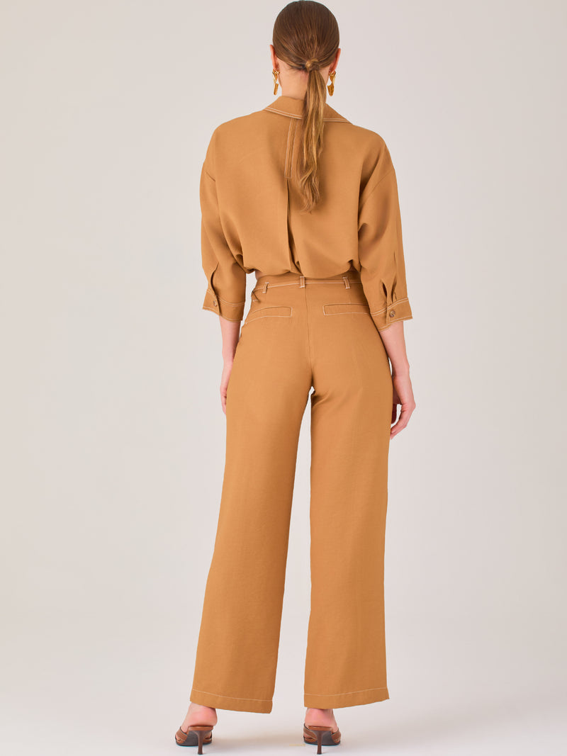 Este pantalón tiene un diseño sofisticado y moderno, confeccionado en un tono beige claro muy versátil. Presenta una silueta de pierna recta y ligeramente amplia, lo que aporta una caída elegante y cómoda. La cintura es de talle medio-alto, con cierre delantero oculto y detalles de pinzas que estilizan la figura. Incluye trabillas para cinturón y bolsillos laterales funcionales, además de costuras marcadas al frente que aportan estructura. Es una prenda ideal para looks de oficina, conjuntos monocromáticos 