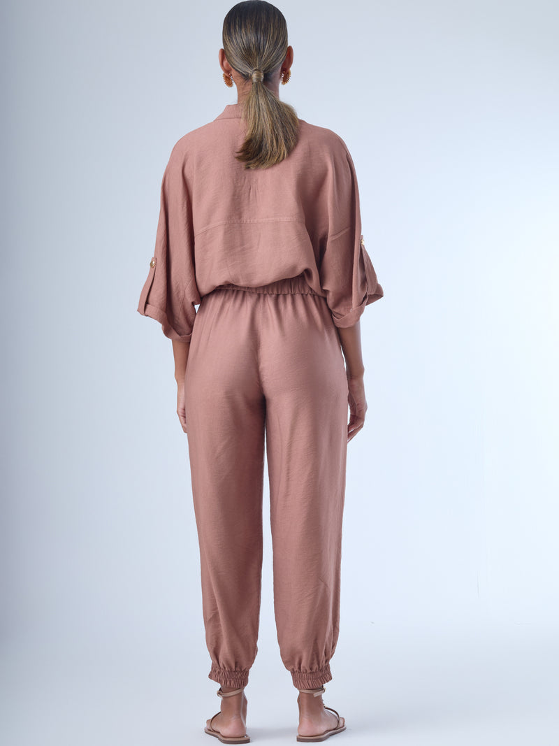 Cómodo y versátil, este pantalón tipo jogger presenta una silueta relajada con ajuste en tobillos y cintura elástica para máximo confort. Los bolsillos frontales tipo parche y la textura suave de la tela lo hacen ideal para looks casuales con un toque elevado. Perfecto para combinar con blusas fluidas o camisas estructuradas, en días de descanso o estilismos urbanos sofisticados.