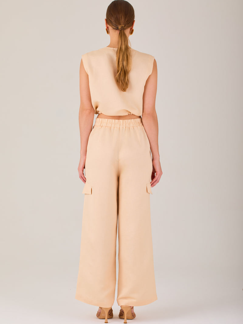 Este pantalón de corte recto y silueta ancha tiene un diseño tipo cargo, con bolsillos de solapa a los costados de las piernas que aportan un toque utilitario. La pretina combina funcionalidad y estilo: es parcialmente elástica en la parte posterior para mayor comodidad, mientras que el frente incluye cierre con botón y pinzas que añaden estructura. Su diseño equilibra lo casual y lo sofisticado, ideal para looks versátiles.