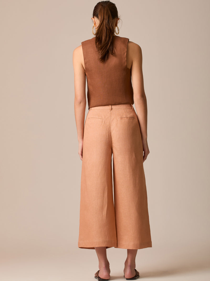 Pantalón de tiro alto con silueta culotte. Pernera amplia y recta con largo cropped al tobillo y dobladillo ancho. Pretina con botón y cierre, bolsillos de parche al frente y pinzas suaves que estilizan la cintura. Versátil y fresco para elevar looks de día o de noche

Detalles:

Color: Peach

Material: 100% Lino
