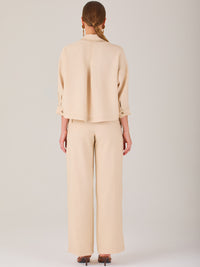 Este pantalón tiene un diseño sofisticado y moderno, confeccionado en un tono beige claro muy versátil. Presenta una silueta de pierna recta y ligeramente amplia, lo que aporta una caída elegante y cómoda. La cintura es de talle medio-alto, con cierre delantero oculto y detalles de pinzas que estilizan la figura. Incluye trabillas para cinturón y bolsillos laterales funcionales, además de costuras marcadas al frente que aportan estructura. Es una prenda ideal para looks de oficina, conjuntos monocromáticos 