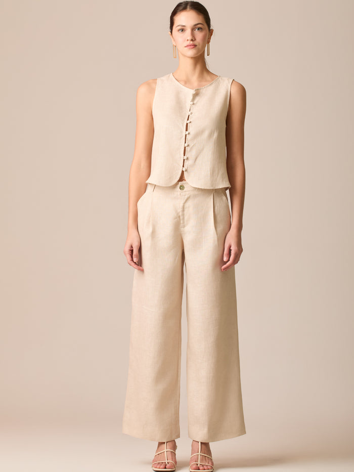 Pantalón de tiro medio con pretina plana, pinzas frontales y corte recto amplio hasta el tobillo, confeccionado en un tejido liviano de textura natural que aporta un look sofisticado y relajado